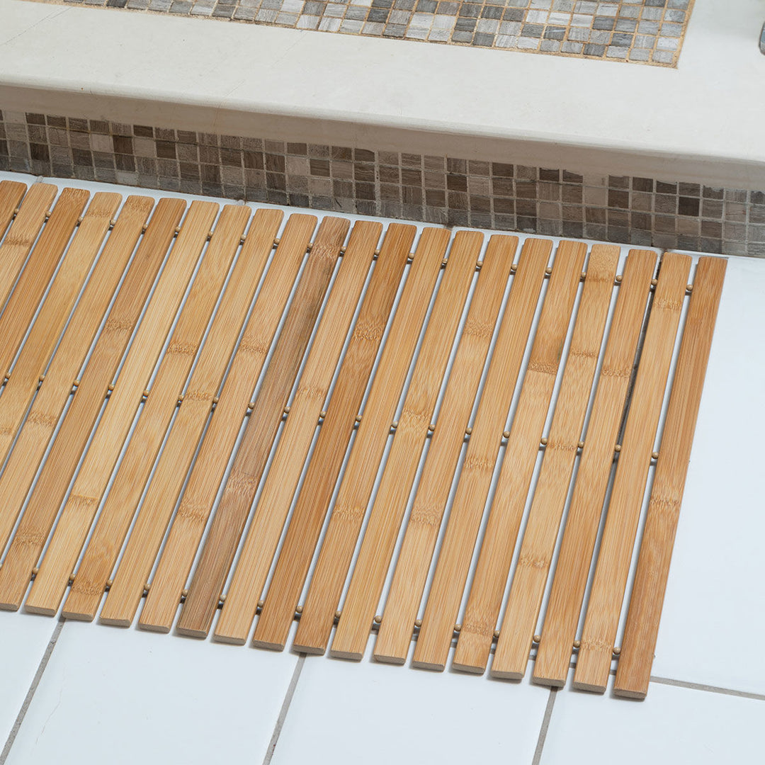 Λεπτομέρεια bamboo χαλιού μπάνιου μπροστά από μπανιέρα, με εμφανή νερά ξύλου και καθαρές γραμμές.