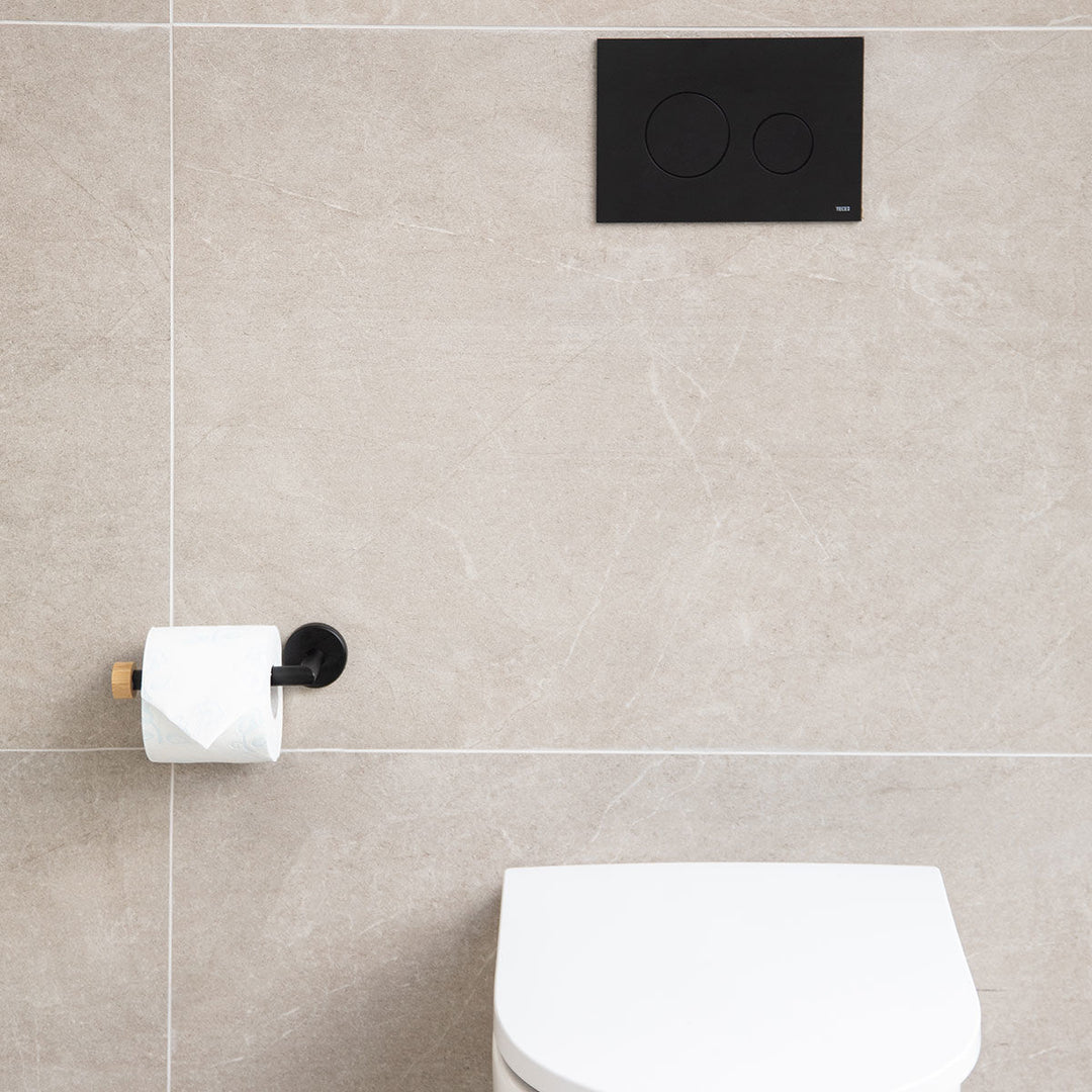 Χαρτοθήκη Bamboo Essentials Estia τοποθετημένη σε μπάνιο με μπεζ πλακάκια και ρολό χαρτιού.