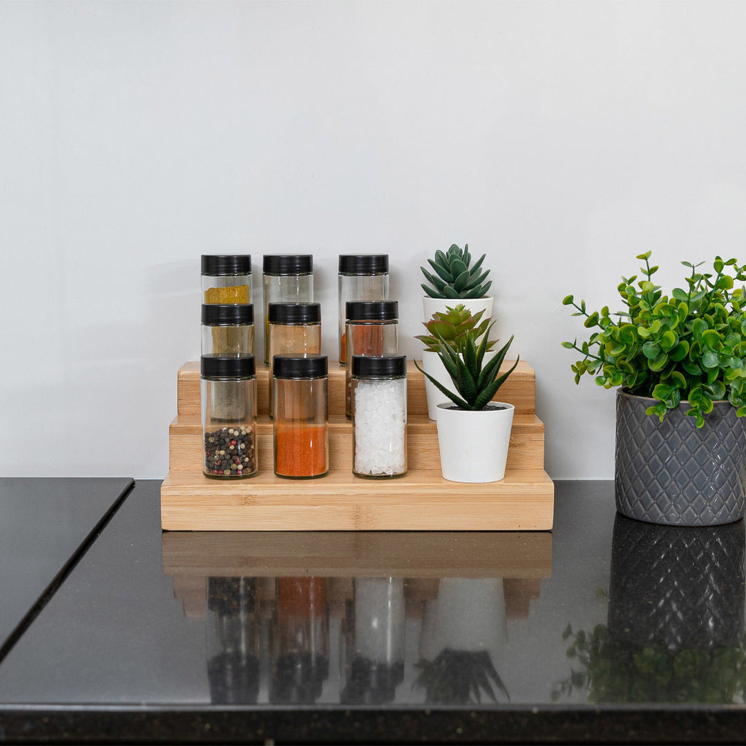 Ξύλινη βάση τριών επιπέδων από bamboo πάνω σε πάγκο κουζίνας, διακοσμημένη με βαζάκια μπαχαρικών και γλαστράκια.