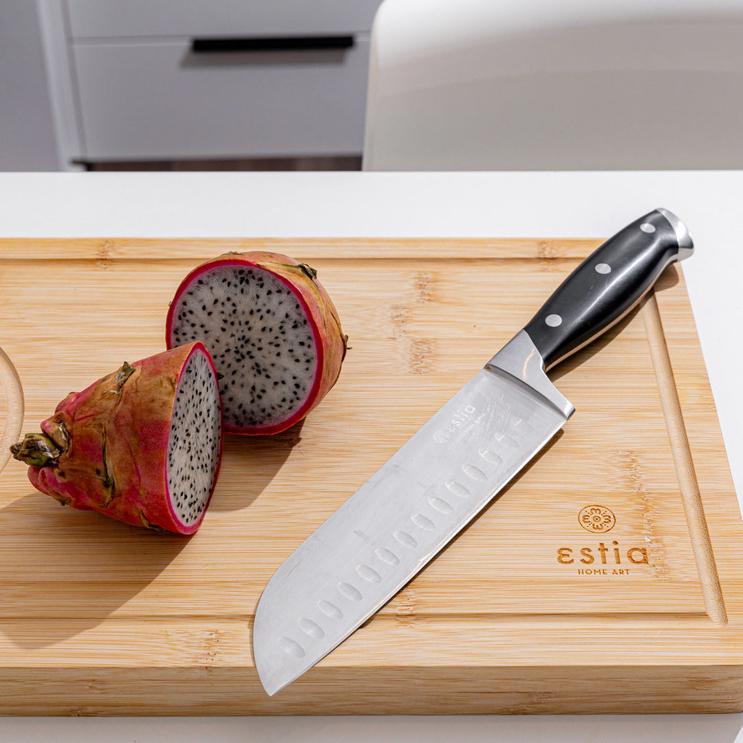 Ξύλινη επιφάνεια κοπής bamboo με μαχαίρι santoku και κομμένο φρούτο dragon fruit, σε φωτεινό πάγκο κουζίνας.