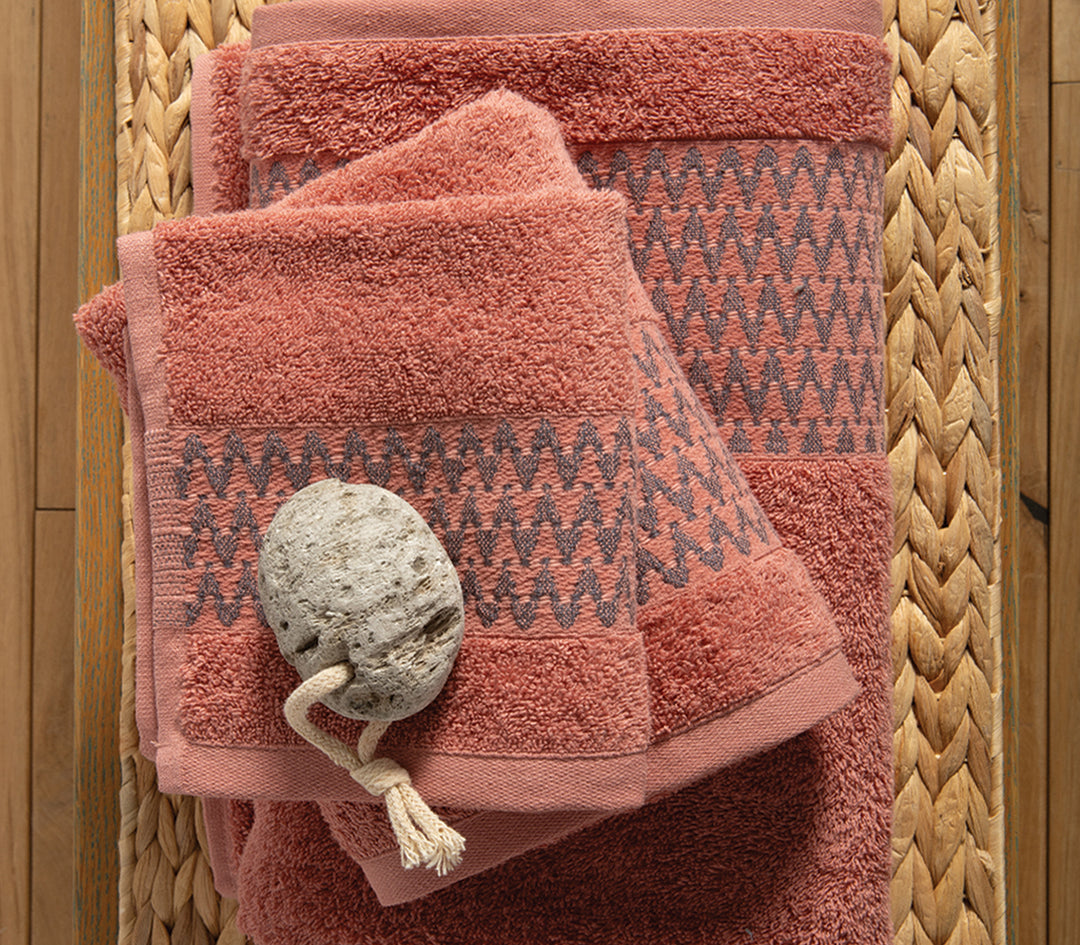 Λήψη από πάνω σε πετσέτες πορτοκαλί με γεωμετρικό σχέδιο, τοποθετημένες επάνω σε ξύλινη επιφάνεια με ψάθινο σουπλά και διακοσμητική πέτρα.