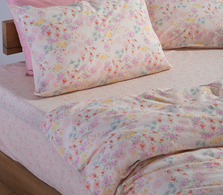 Ροζ παιδικά σεντόνια Blossom Day της Nef-Nef Homeware στρωμένα σε κρεβάτι με λουλουδάτο σχέδιο.