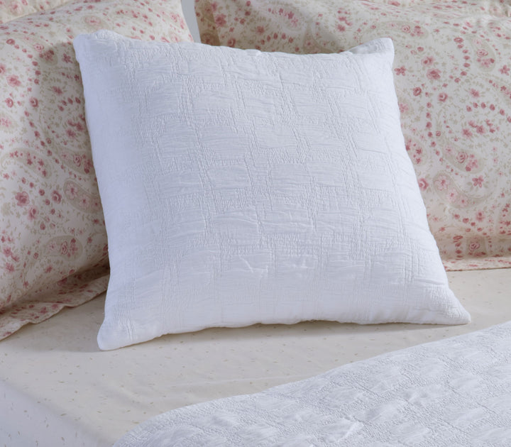 Λευκή διακοσμητική μαξιλαροθήκη Nef-Nef Homeware τοποθετημένη σε κρεβάτι με floral σεντόνια δημιουργώντας φωτεινή και ρομαντική ατμόσφαιρα.