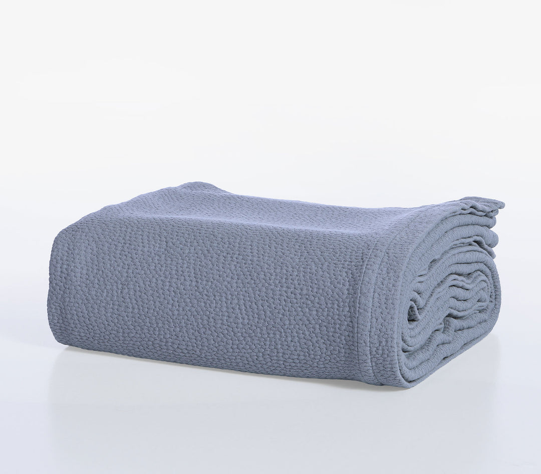 Διπλωμένη βαμβακερή κουβέρτα Nef-Nef Homeware σε μπλε χρώμα με ανάγλυφη υφή υφάσματος.