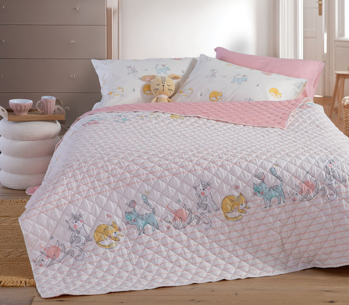 Παιδικό κουβερλί Cat Life της Nef-Nef Homeware σε εκρού και ροζ χρώμα στρωμένο σε παιδικό κρεβάτι με μαξιλάρια και λούτρινο παιχνίδι.