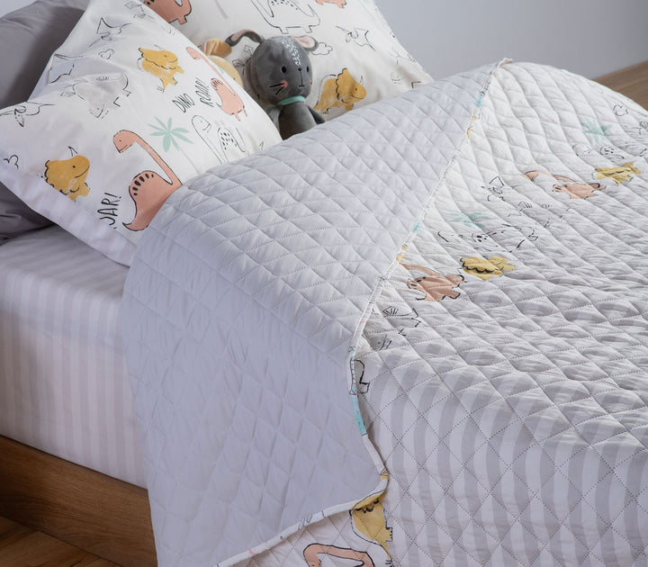 Παιδικό κουβερλί Dinosaur Art της Nef-Nef Homeware σε εκρού και γκρι αποχρώσεις τοποθετημένο σε παιδικό δωμάτιο.