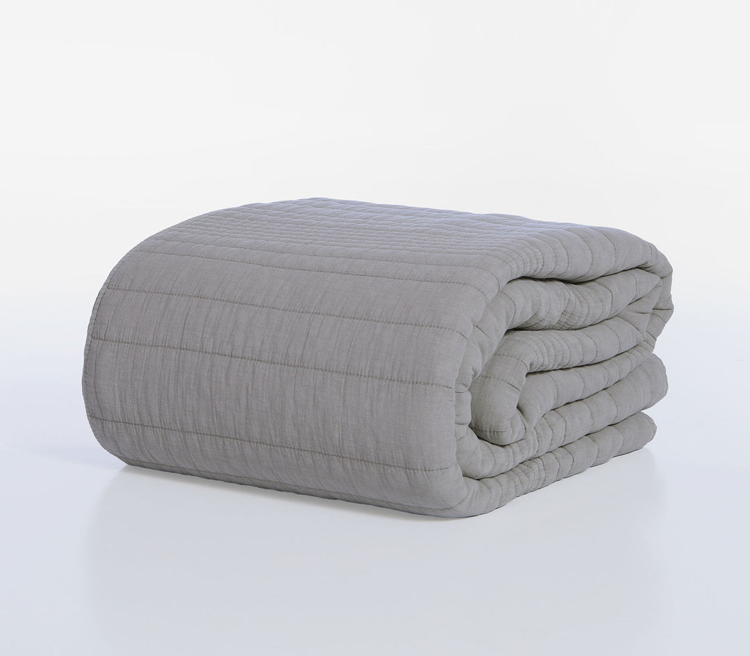 Διπλωμένο γκρι κουβερλί Nef-Nef Homeware με καπιτονέ ραφές τοποθετημένο πάνω σε λευκό φόντο στούντιο.