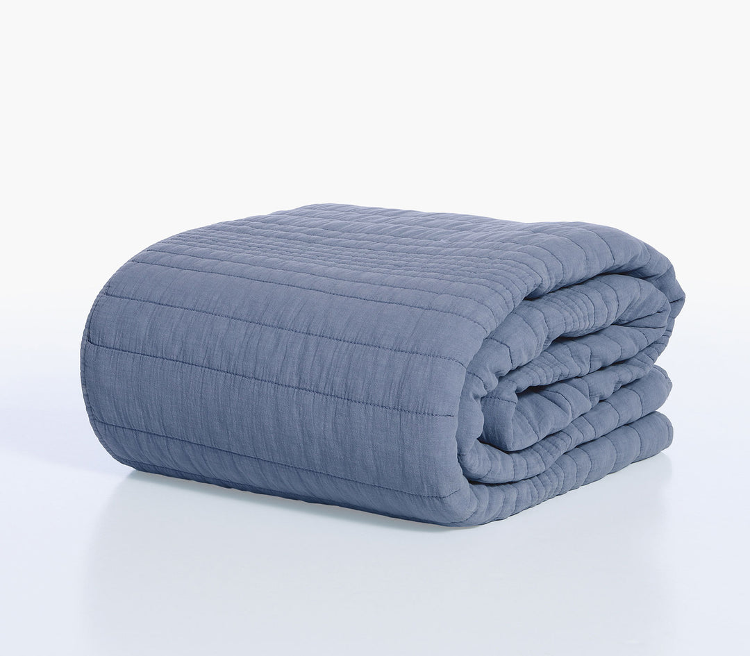 Διπλωμένο κουβερλί Nef-Nef Homeware σε μπλε απόχρωση με καπιτονέ υφή και ομοιόμορφες ραφές πάνω σε λευκό φόντο.