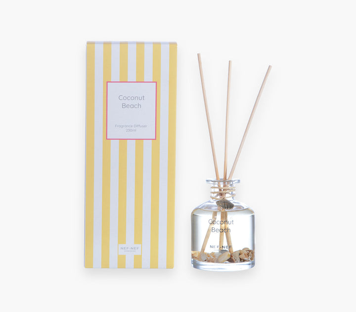 Αρωματικό χώρου με στικς Coconut Beach της Nef-Nef Homeware σε γυάλινο μπουκάλι με κοχύλια και κίτρινη ριγέ συσκευασία.