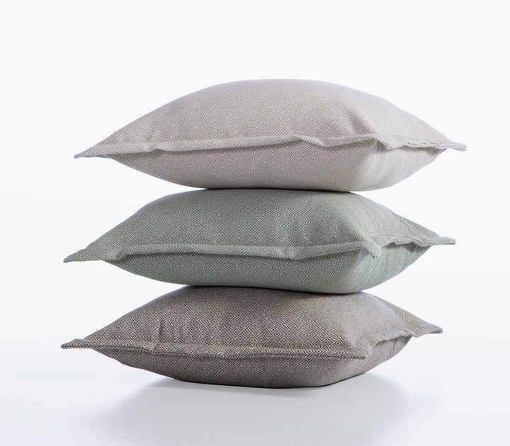 Στοίβα διακοσμητικών μαξιλαριών Loen της Nef-Nef Homeware σε μπεζ, γκρι και πράσινη απόχρωση με υφαντό γεωμετρικό μοτίβο.