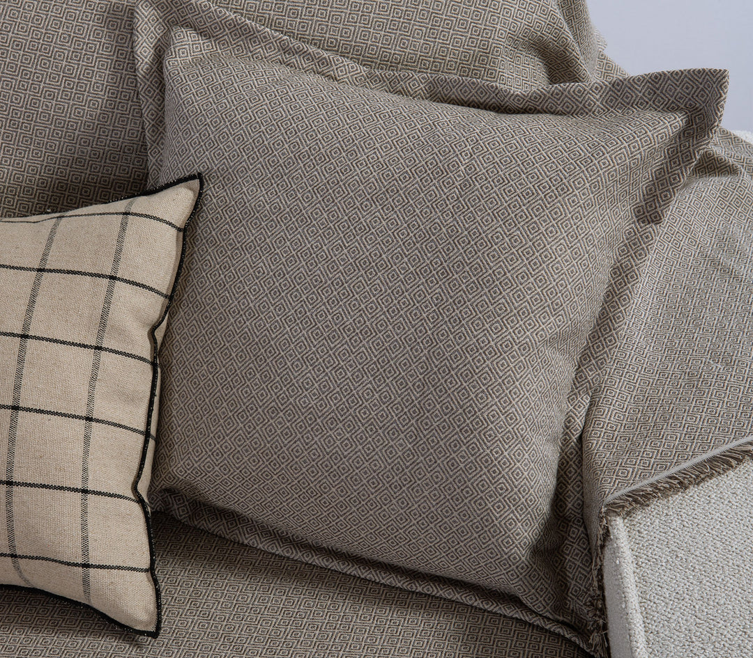 Γκρι διακοσμητικό μαξιλάρι Loen της Nef-Nef Homeware με διακριτικό γεωμετρικό μοτίβο τοποθετημένο σε καναπέ με ριχτάρι ίδιας σειράς.