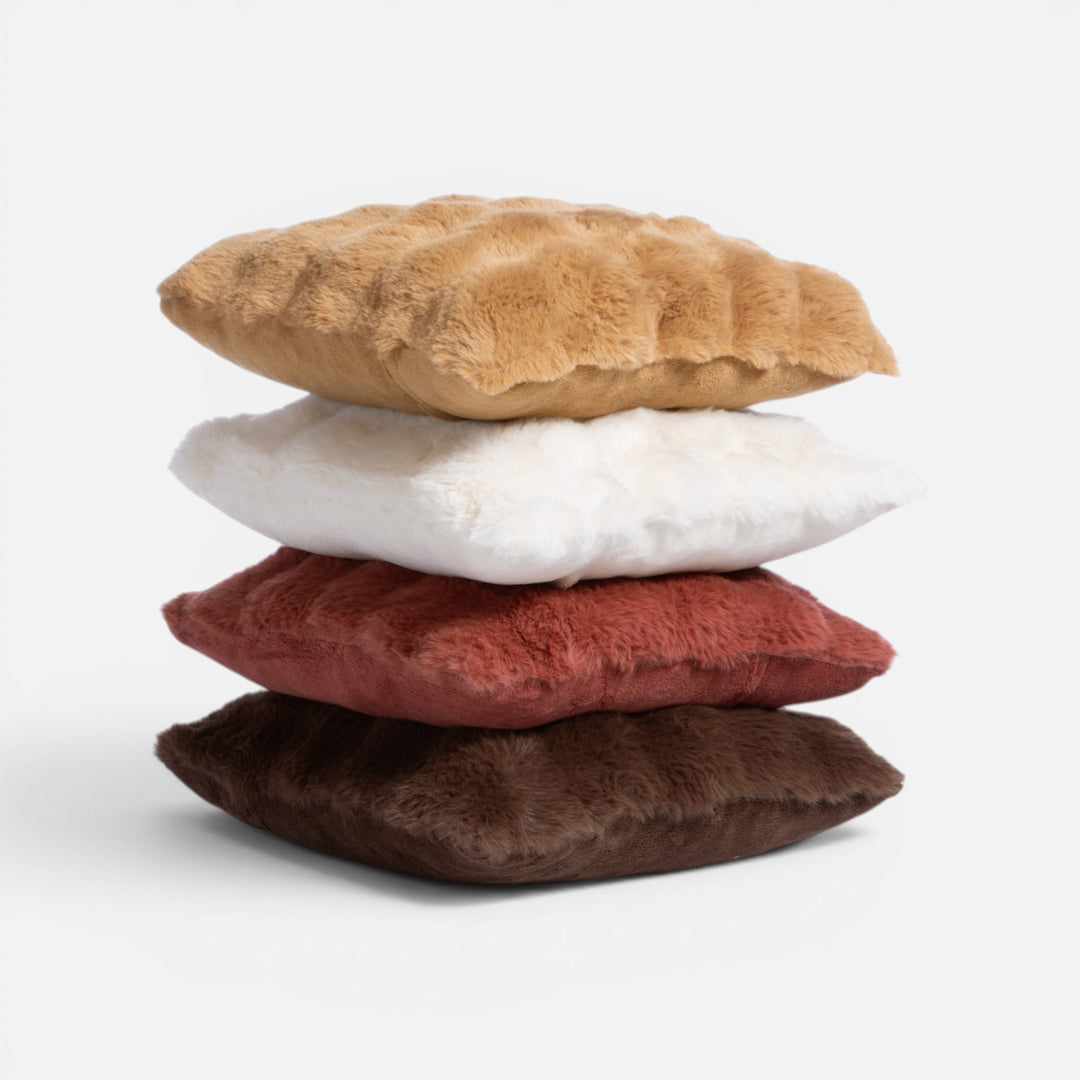 Στοίβα από γούνινα διακοσμητικά μαξιλάρια σε καραμελί, εκρού, κεραμιδί και καφέ αποχρώσεις, με απαλή χνουδωτή υφή.
