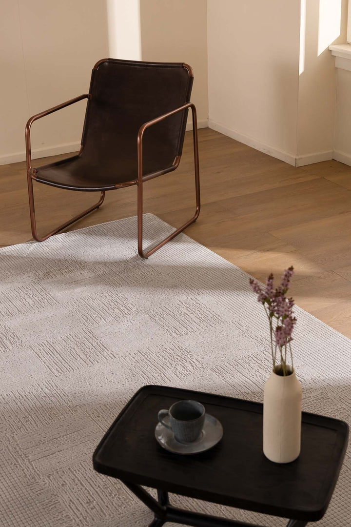 Γκρι χαλί σε ξύλινο δάπεδο, διακοσμημένο με καρέκλα και τραπεζάκι με βάζο και κούπα.