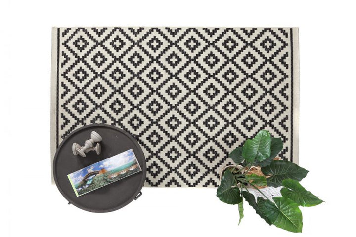 Ασπρόμαυρο ψάθινο χαλί Flox Royal Carpet διακοσμημένο με μοντέρνο δίσκο και πράσινο φυτό σε minimal φόντο.