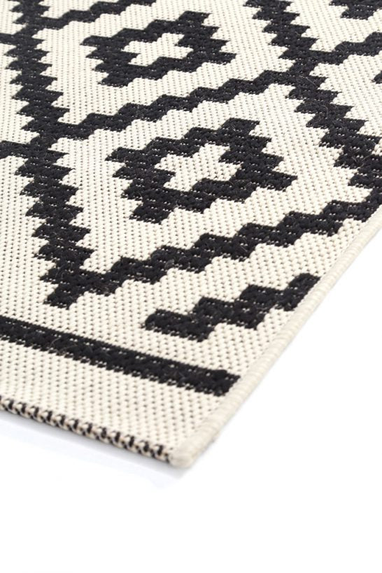 Κοντινή λήψη σε ψάθινο χαλί Flox Royal Carpet με μαύρα γεωμετρικά σχέδια και λεπτομέρεια ύφανσης πολυπροπυλενίου.
