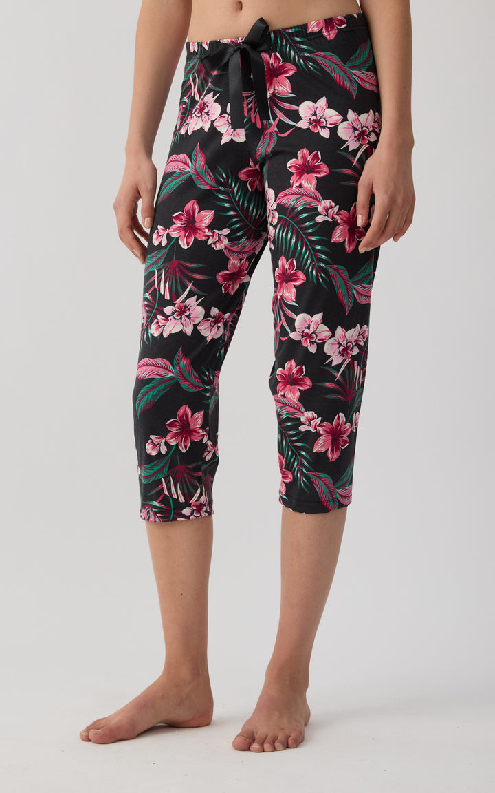 Γυναικείο βαμβακερό κάπρι παντελόνι Minerva με floral tropical σχέδιο και μαύρη σατέν κορδέλα σε λευκό φόντο.